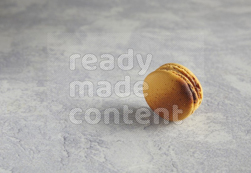 45º Shot of Yellow Crème Brulée macaron on white marble