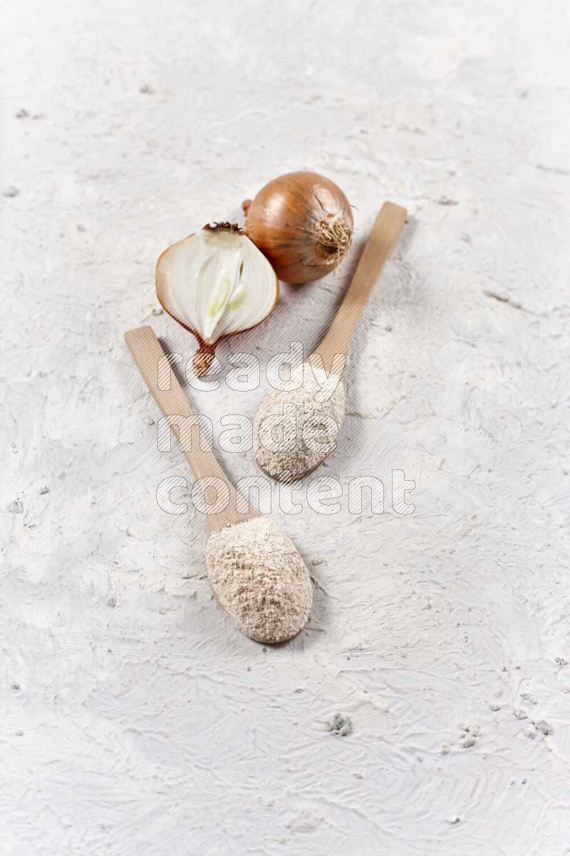 Two wooden spoons full of onion powder on white background