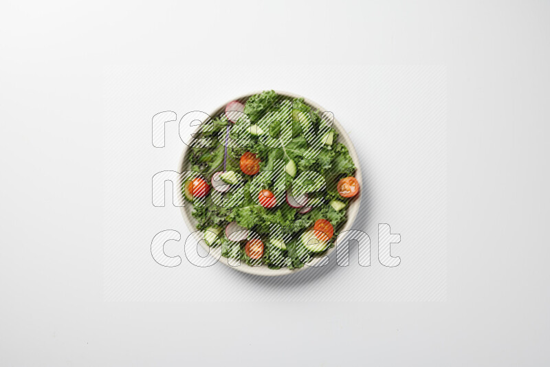 A bowl of fresh vegetables salad with kale leaves, cherry tomatoes, sliced radishes and sliced cucumber on a white background
