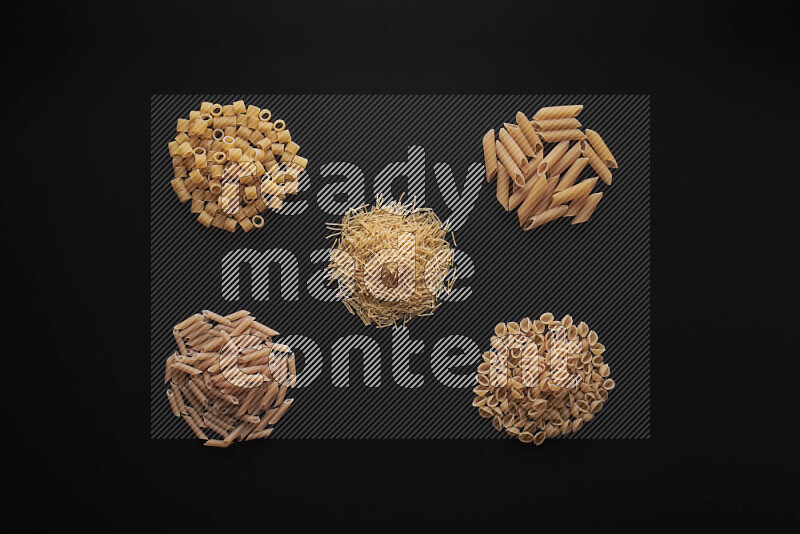 Different pasta types in bunches on black background