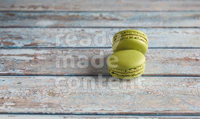 45º Shot of two Green Pistachio macarons on light blue wooden background