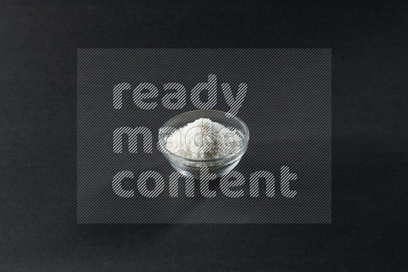 A glass bowl full of desiccated coconut on a black background in different angles