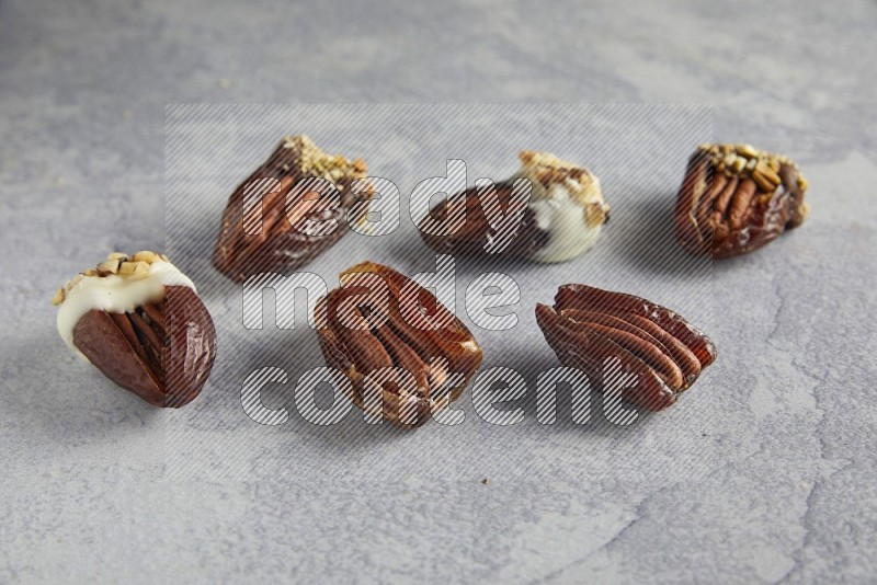 group of pecan stuffed dates plain and covered with dark and white chocolate  on alight grey background
