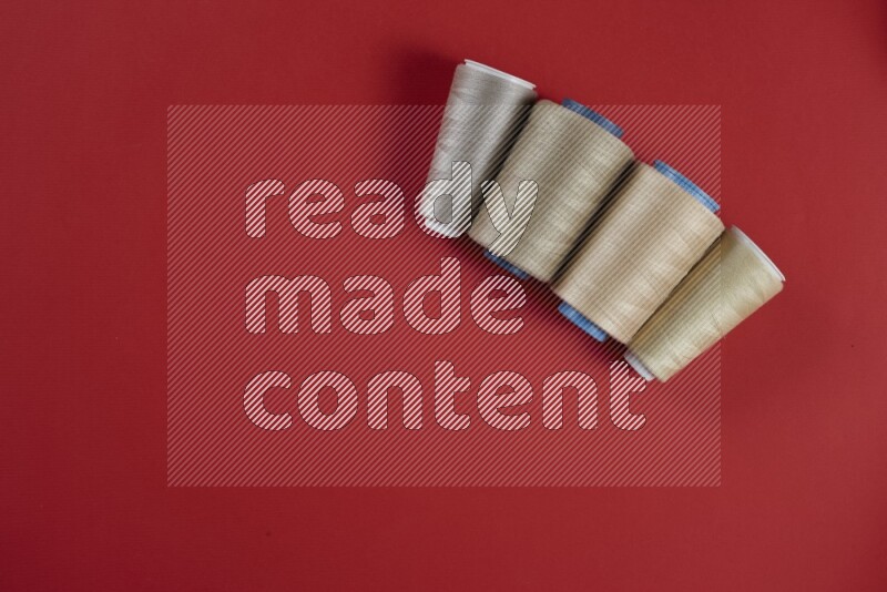 A brown and red collection of sewing and tailoring tools arranged on a red background