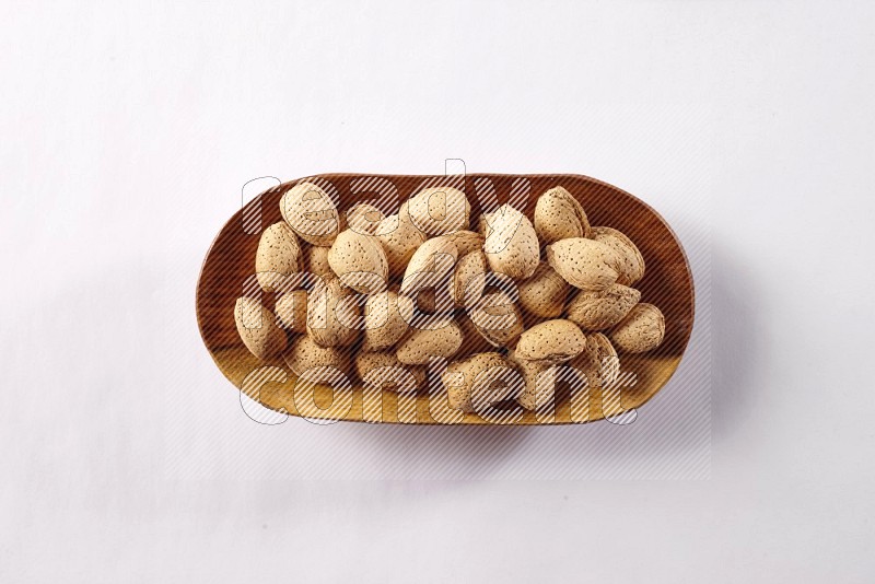 Almonds in a wooden plate on white background