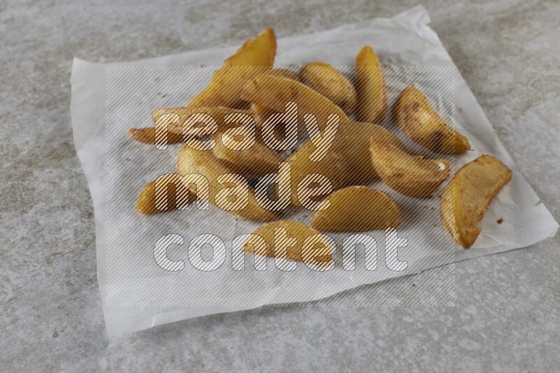 wedges potato on parchment paper on grey textured counter top