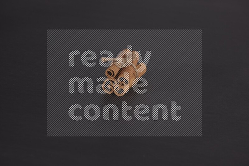 4 Cinnamon sticks stacked and bounded on black flooring