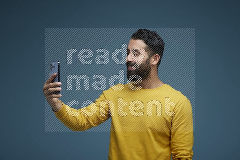 Man Taking a Selfie  in a blue background wearing a yellow shirt