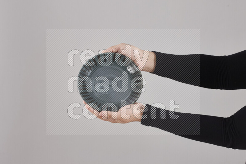 A woman in black abaya holding different pottery essentials in different positions