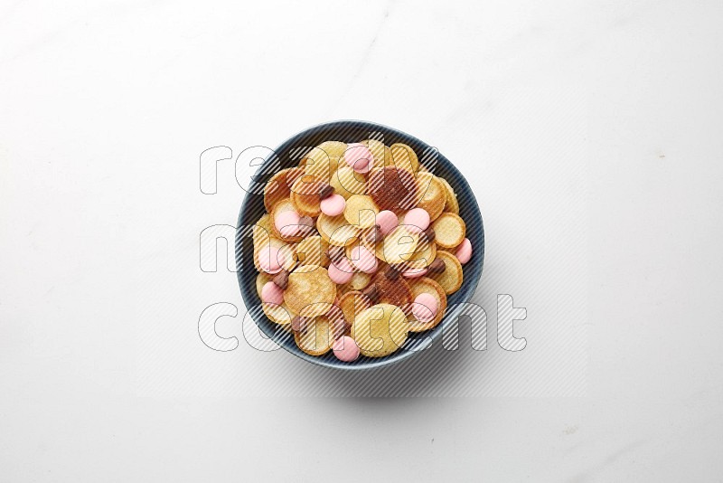 Top-view shot of mixed chocolate chips cereal pancakes in a round bowl on white background