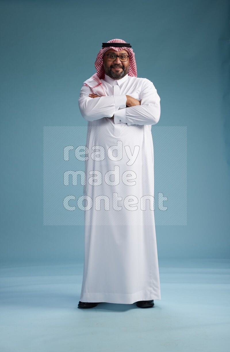 Saudi Man with shimag Standing Interacting with the camera on blue background