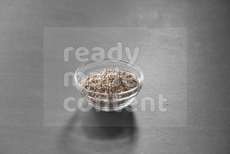 A glass bowl full of white peppers on black flooring