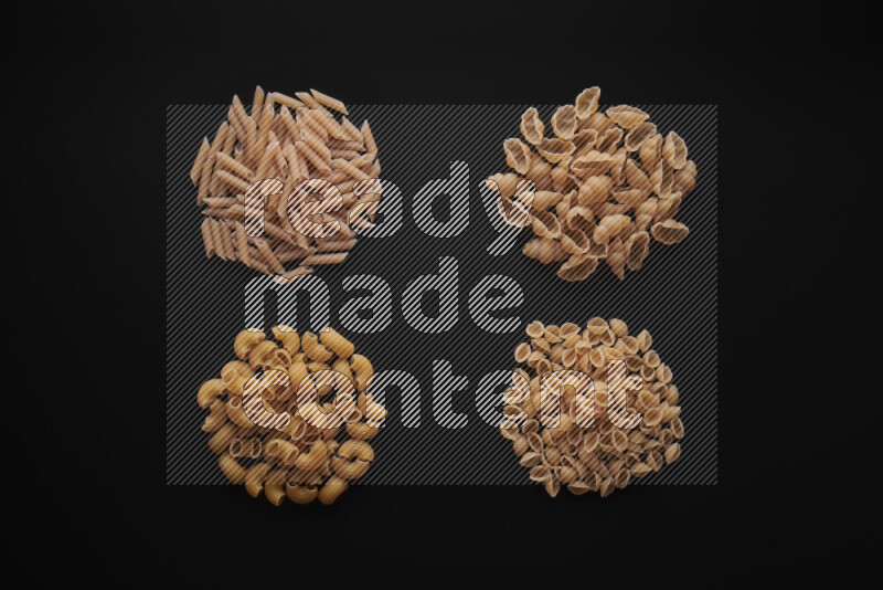 Different pasta types in bunches on black background