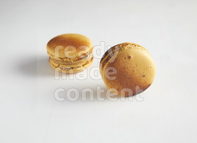 45º Shot of two Yellow Crème Brulée macarons on white background