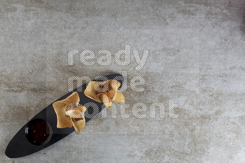 wonton cups with soy sauce ramkin on oval slate on grey textured counter top