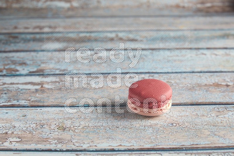 45º Shot of Pink Litchi Raspberry macaron on light blue wooden background