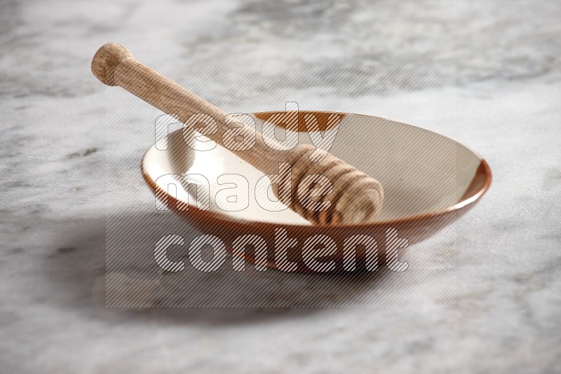 Multicolored Pottery Plate with wooden honey handle in it, on grey marble flooring, 15 degree angle