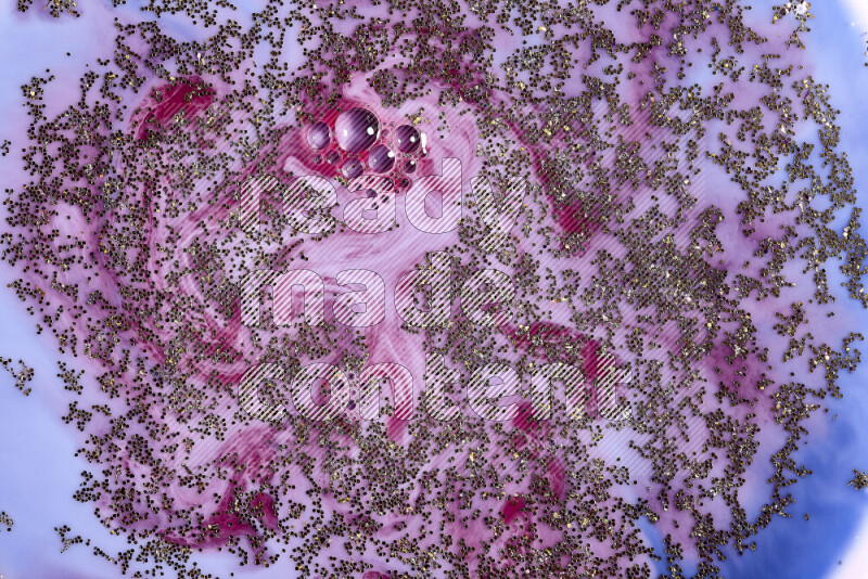 لقطة مقربة لبريق ذهبي متلألئ منتشر على خلفية من اللون الأزرق والأحمر في حركات دائرية