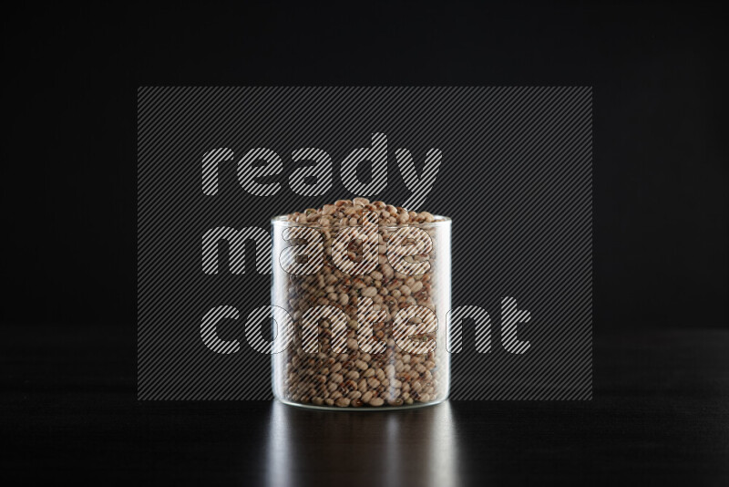 Black-eyed peas in a glass jar on black background