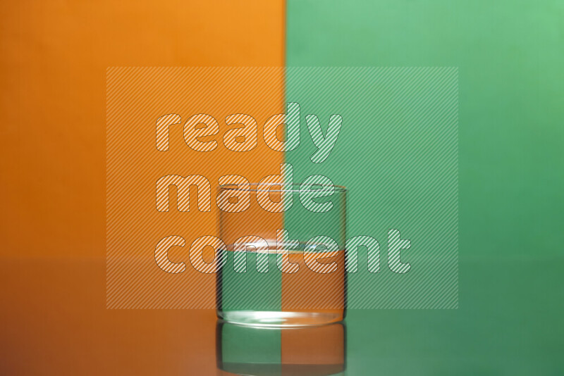 تظهر الصورة أواني زجاجية ممتلئة بالماء موضوعة على خلفية من اللونين البرتقالي والأخضر