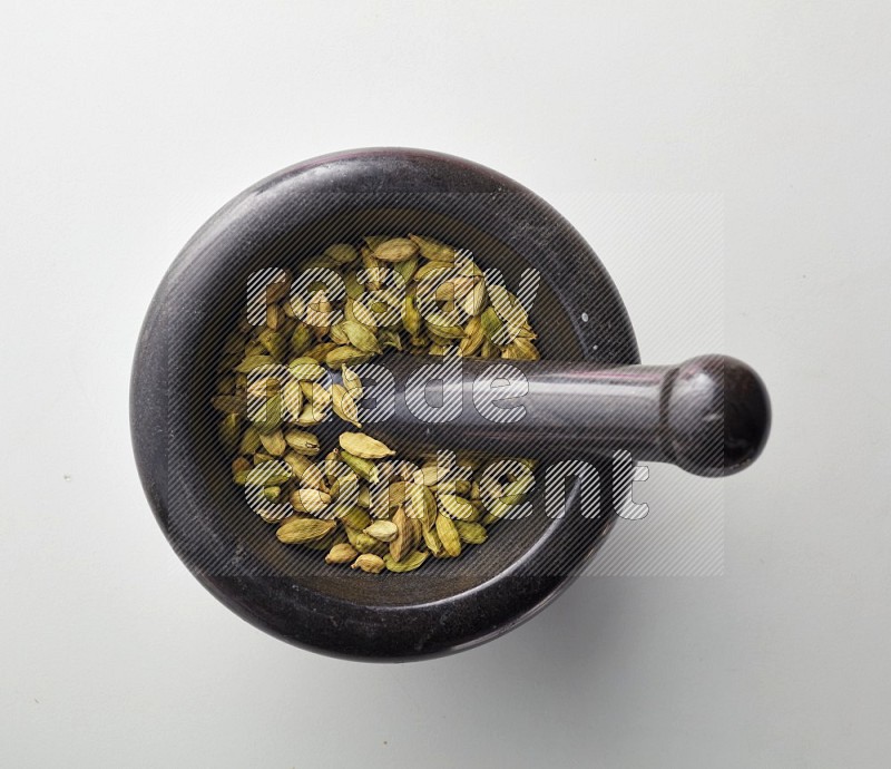 Top-view shot of Cardamon in herbs crusher on white background