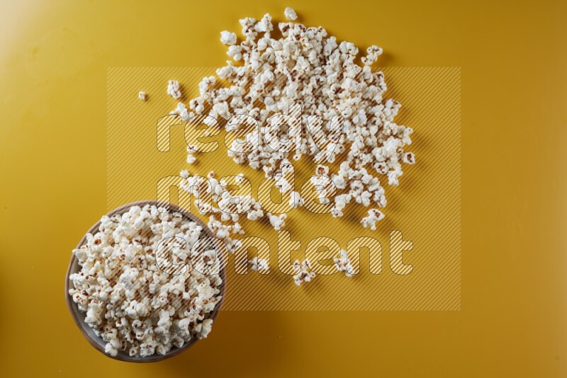 A brown pottery bowl full of popcorn with popcorn beside it on a yellow background in different angles
