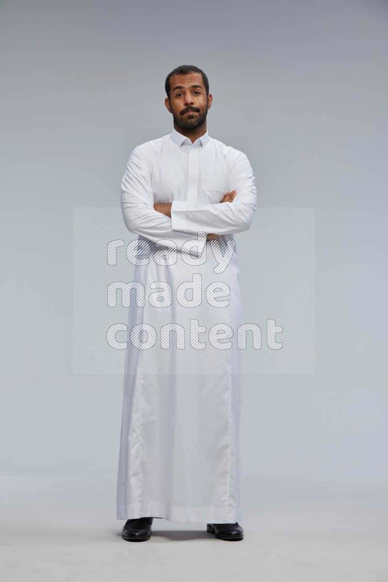 Saudi man wearing Thob standing with crossed arms on Gray background