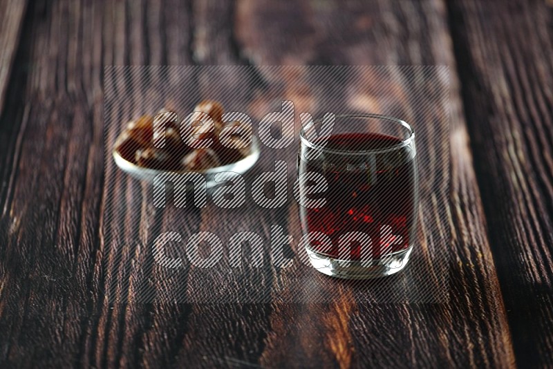 Cold drinks in a glass cup with dates such as water, tamarind, qamar eldin, sobia, milk and hibiscus on wooden background