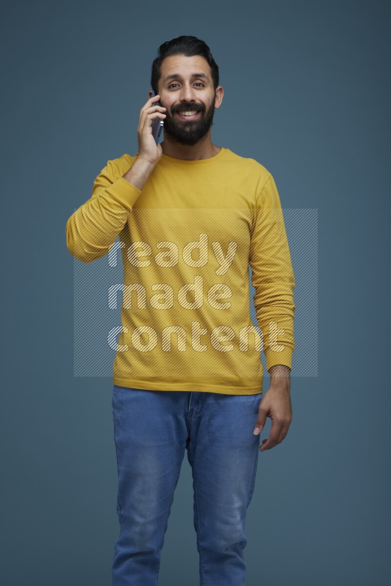 A man having a calling in a blue background wearing a yellow shirt