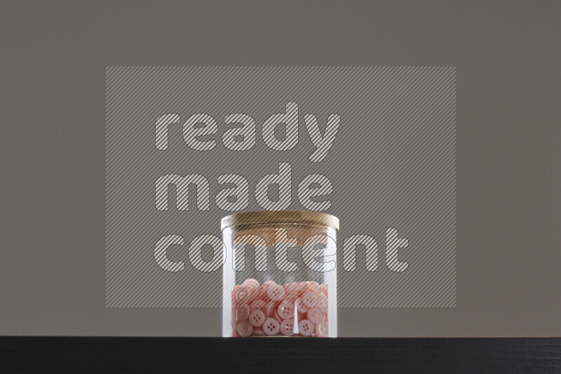 أزرار متنوعة في وعاء زجاجي علي خلفية سوداء