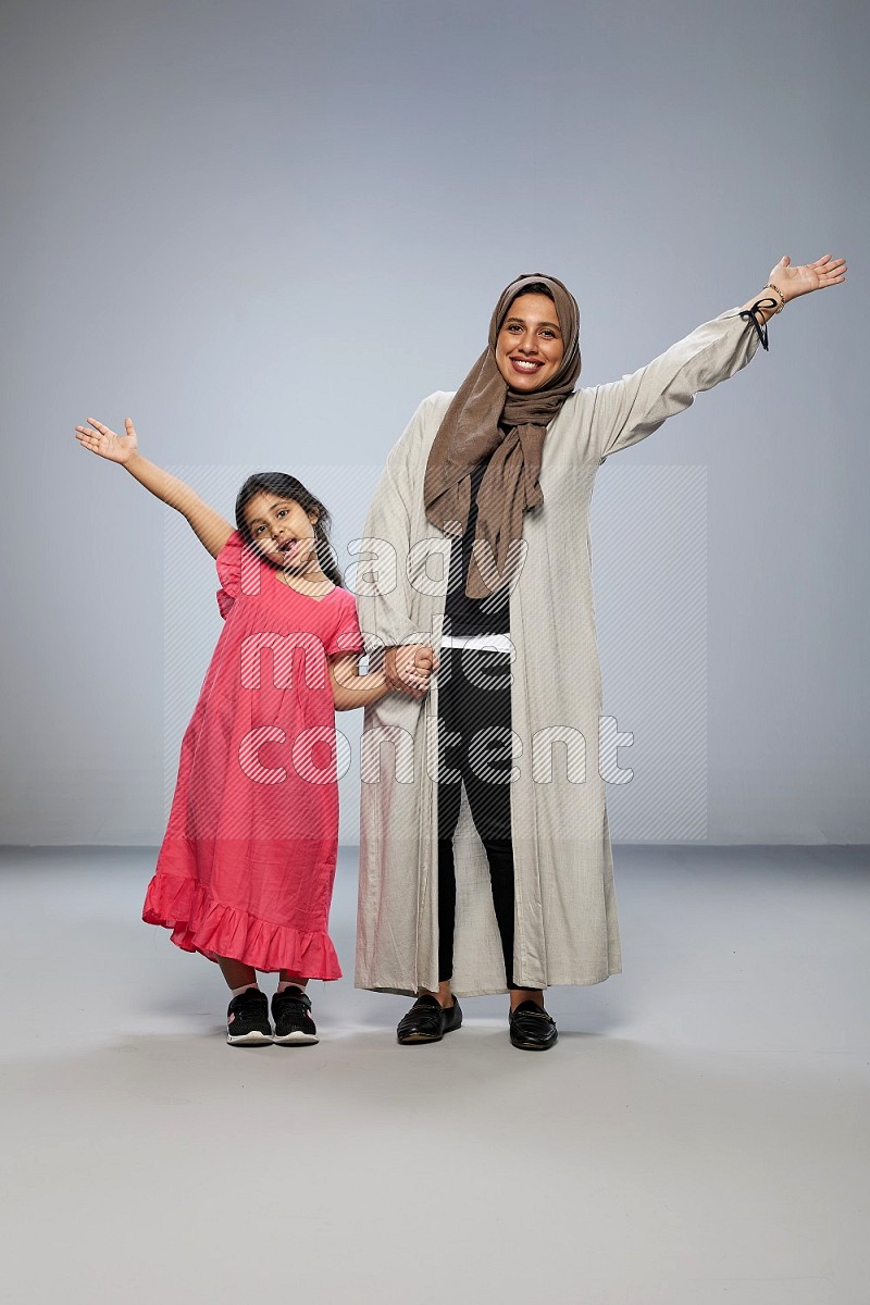 A girl and her mother interacting with the camera on gray background