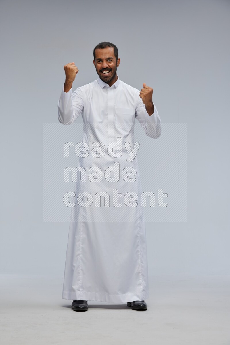 Saudi man Wearing Thob standing interacting with the camera on Gray background