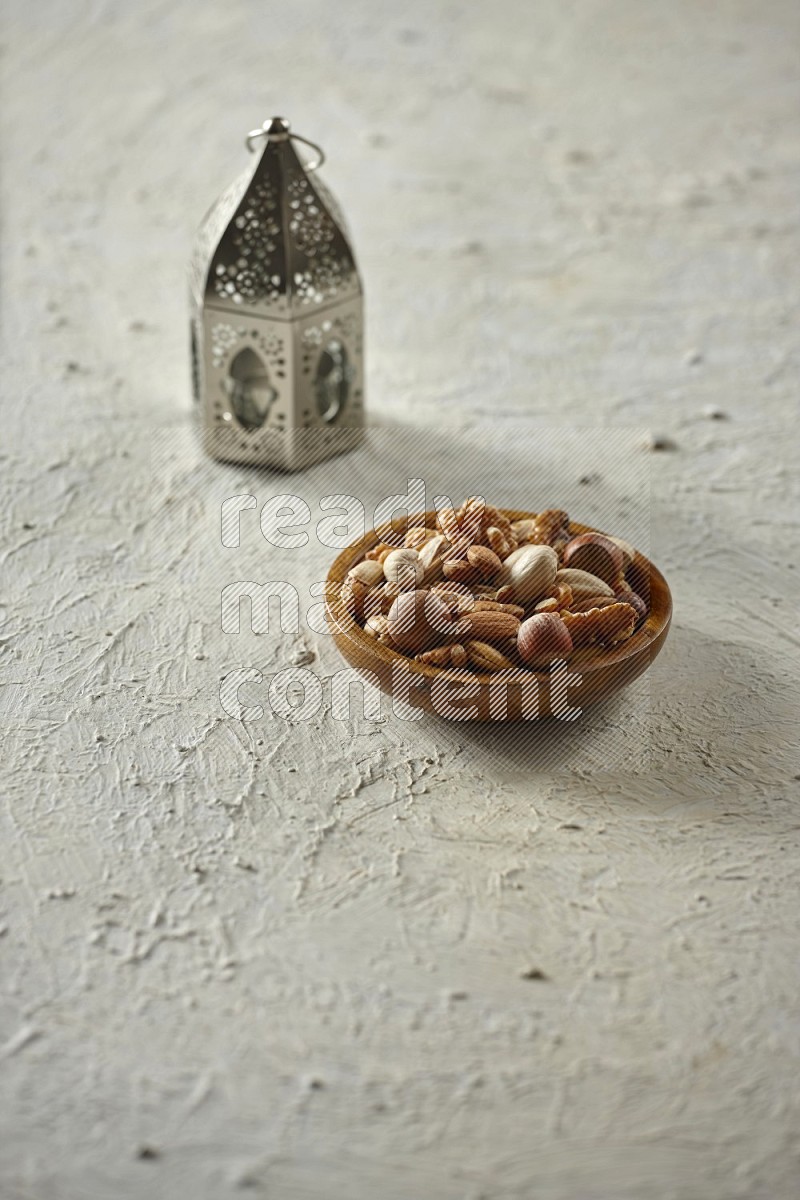 A silver lantern with drinks, dates, nuts, prayer beads and quran on textured white background