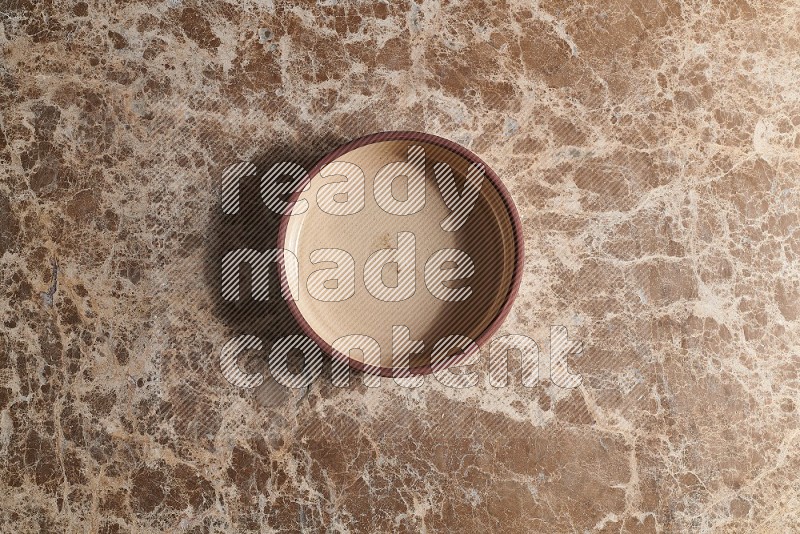 Top View Shot Of A Beige Pottery Oven Plate On beige Marble Flooring