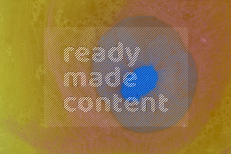 The image captures a dramatic splatter of blue paint over a orange backdrop