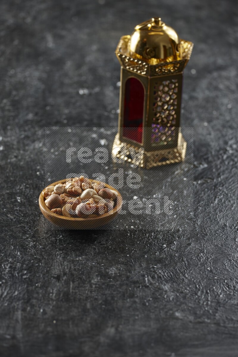 A golden lantern with different drinks, dates, nuts, prayer beads and quran on textured black background