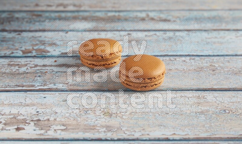 45º Shot of two Brown Maple Taffy macarons on light blue wooden background