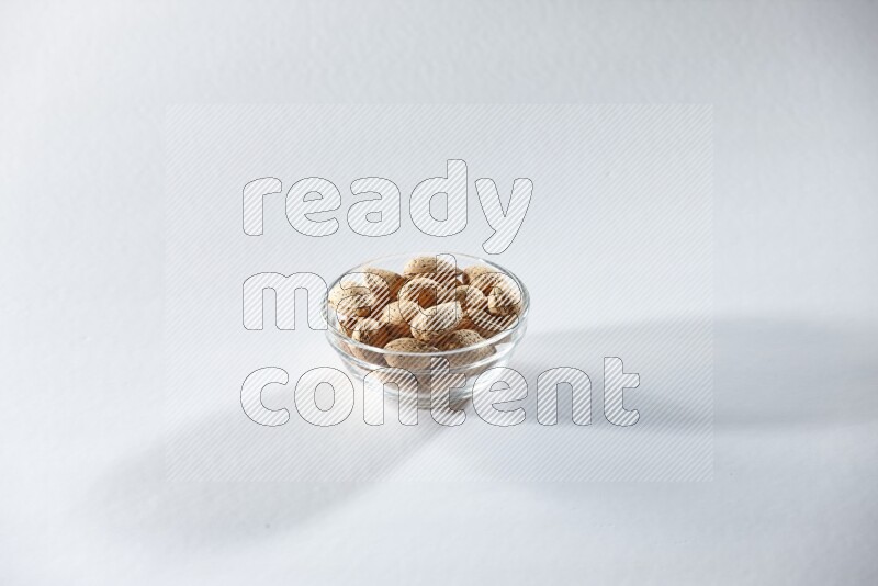 A glass bowl full of almonds on a white background in different angles