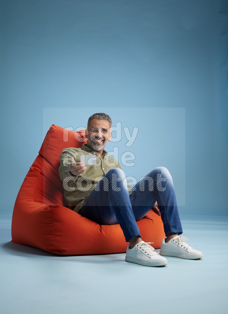 A man sitting on an orange beanbag and holding ATM card