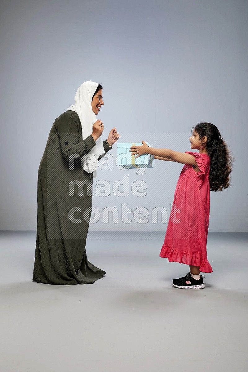 A girl giving a gift to her mother on gray background