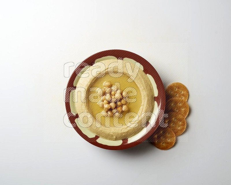 Hummus in a traditional plate garnished with roasted chickpeas  on a white background