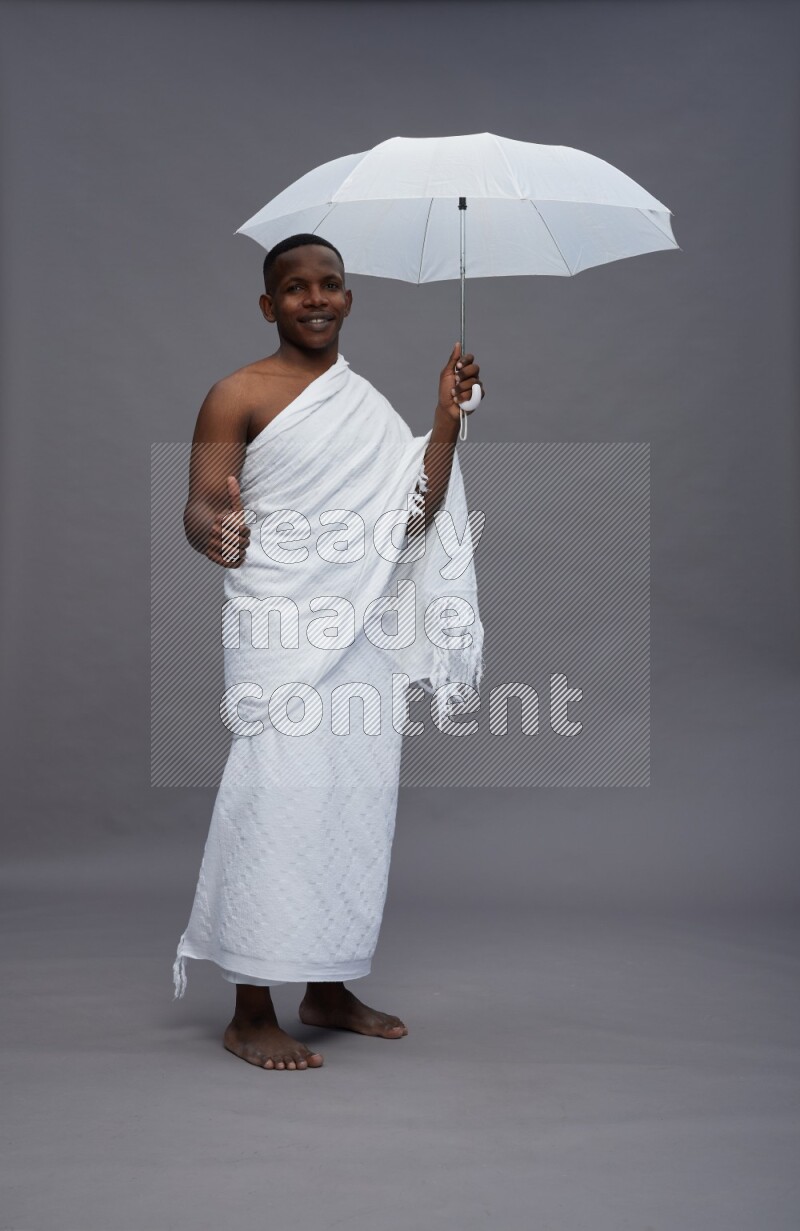 A man wearing Ehram Standing holding umbrella on gray background