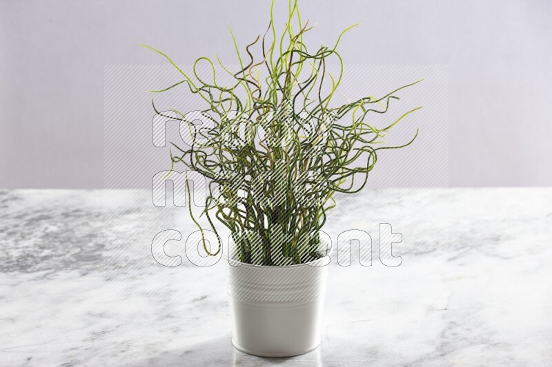 Green artificial plant in white pot on light grey marble background