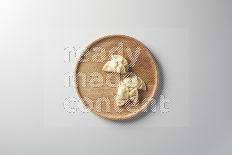 Five Sambosas on a wooden round plate on a white background