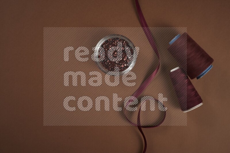 مجموعة من أدوات الخياطة والتفصيل حمراء اللون على خلفية بنية