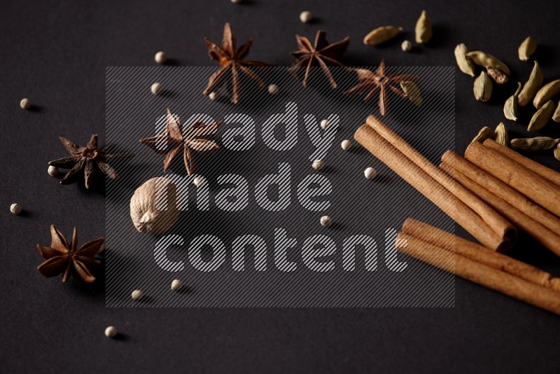 Cinnamon sticks, cardamom, star anise, nutmeg and white peppers on a black background