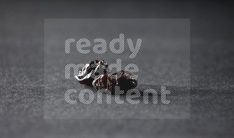 Two dried plums on a black background in different angles