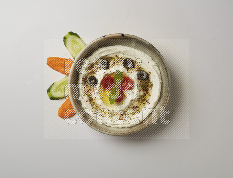 Lebnah garnished with cherry tomato, mint, olives & pine nuts in a grey pottery plate on a white background