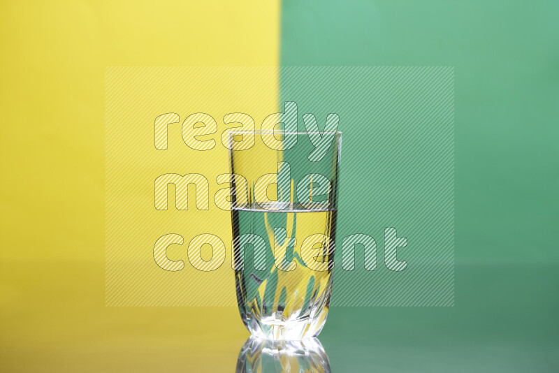 The image features a clear glassware filled with water, set against yellow and green background