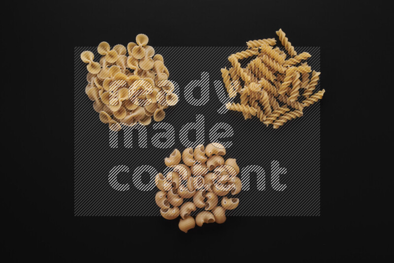 Different pasta types in bunches on black background